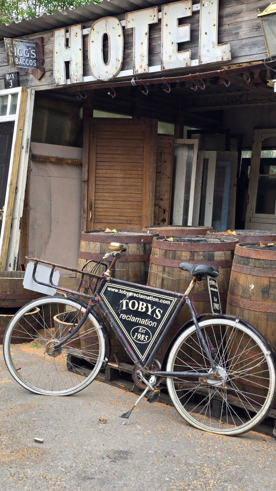 Vintage bicycle with a sign in front of a rustic Devon reclamation yard